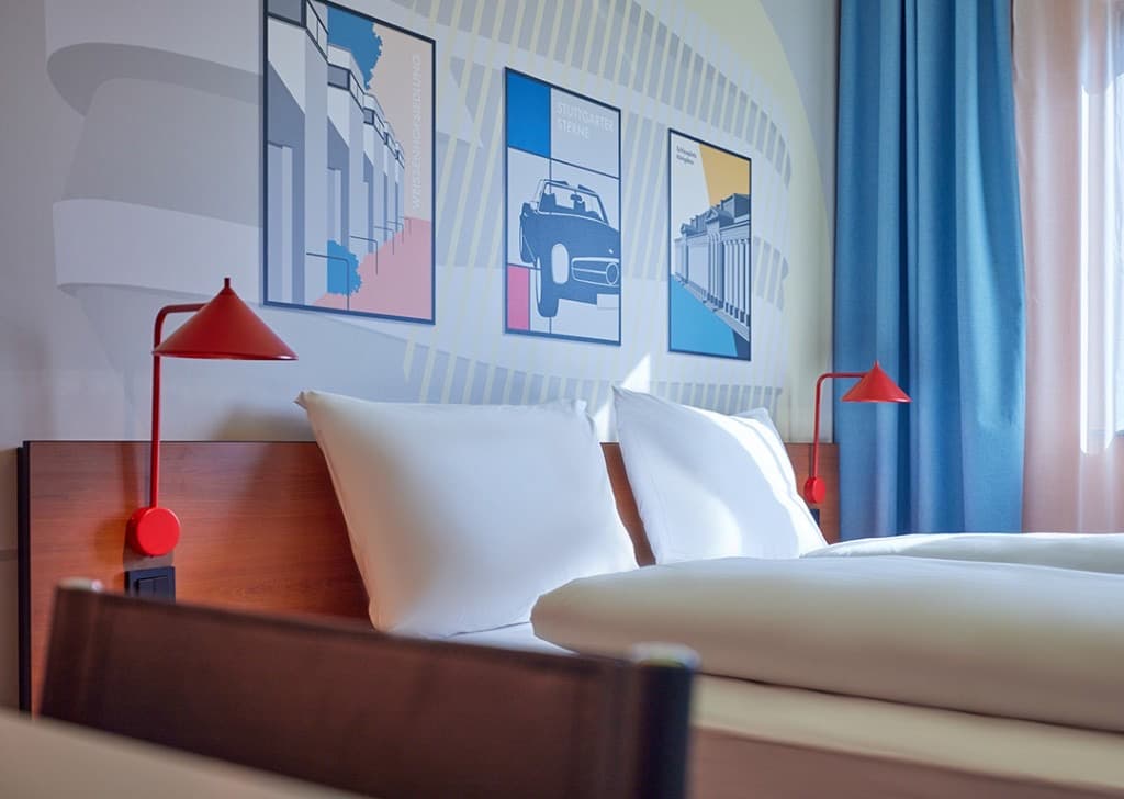 McDreams hotel room with modern furnishings, red wall lamps, and Stuttgart-themed artwork