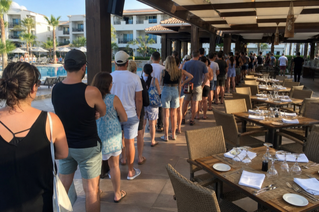 Pool restaurant terrace with empty tables and a long queue of waiting guests